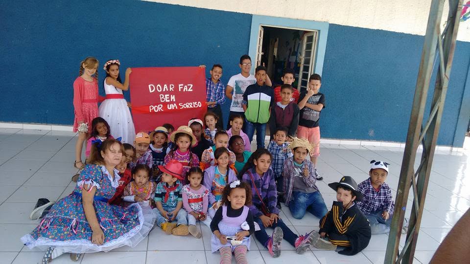 Crianças do CIS com o cartaz Doar faz bem por um sorriso